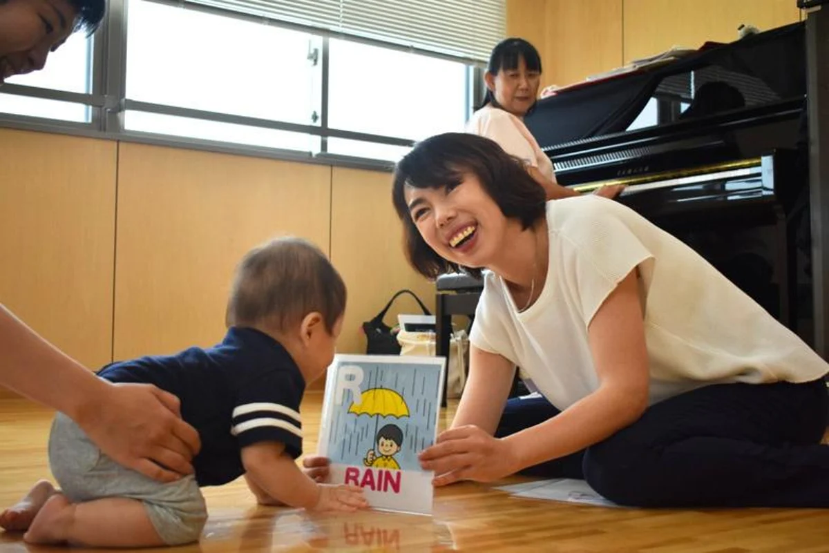グランドピアノのある教室で、先生と子どもが教具を使って遊ぶ様子